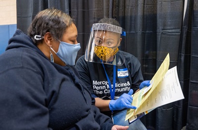 Dr. Meghan Lane-Fall explaining the vaccine consent form to female patient at the West Philly community vaccine clinic 